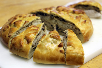 Chicken pie with rice and mushrooms, cut into pieces. Freshly baked kurnik on the table, traditional russian pie © Oleg