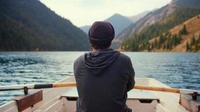 Hipster man is padding on the small boat or canoe in middle of lake and green pine woods forest mountains in nature of Asia in awaited active vacations holidays Feel calm relax desconection and sport
