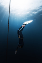 Freediver in monofin descends into depth along the anchor chain in the sea. Version of the photo...
