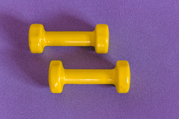 Yellow dumbbells pink fitness mat. Concept of fitness and weight loss.