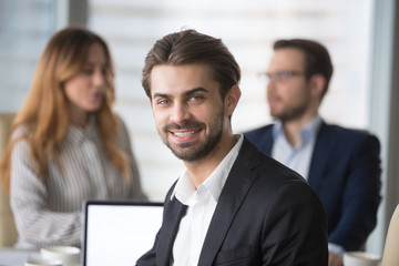Smiling businessman in suit looking at camera posing at meeting