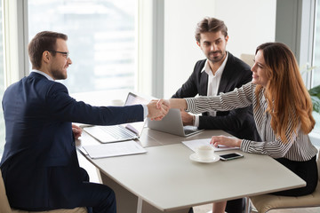 Businessman handshaking businesswoman making deal finishing group negotiations