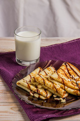 Three pancakes on a plate with chocolate sauce