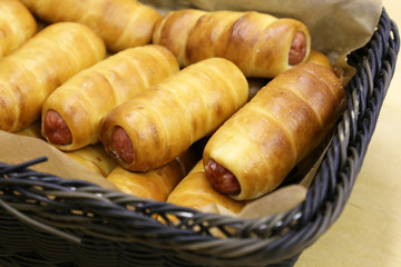 Sausages in the dough in a wicker basket. Fresh pastry, bakery concept