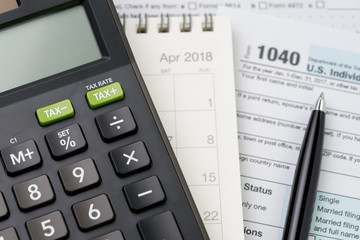 Selective focus on calculator on calendar Pen and 1040 US individual income tax filling form, tax submission or revenue calculation concept