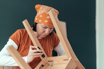 Female carpenter repairing wooden chair seat in workshop