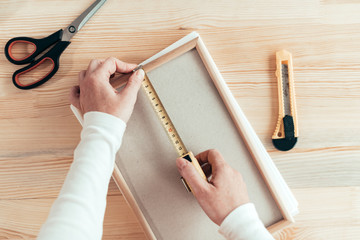 Female carpenter tape measuring picture frame in workshop