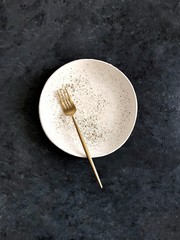 empty white plate with knife and fork on dark background