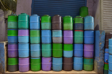 Colorful plastic water jugs stacked on top of each other against closed shutters in a market in Chandni Chowk, Old Delhi, India during Corona virus disease (Covid-19) pandemic lock down