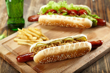 Two hot dogs with french fries on wooden cutting board. Junk food