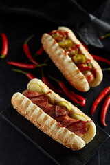 Hot dog with jalapeno and red hot chilli peppers on black  background