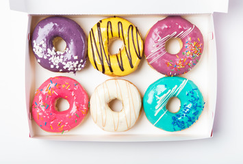 Six donuts with glaze in different colors in a white box