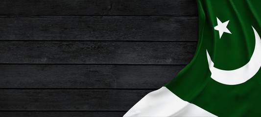 Flag of Pakistan, fabric on dark wood. - obrazy, fototapety, plakaty