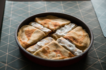 Food preparing in a countryside. Stuffed pancakes, cream and dried meat.