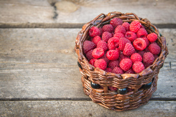 ripe raspberries in a basket on a wooden background