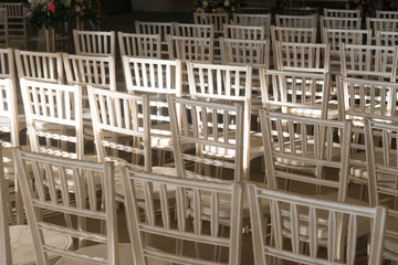 A view of rows of empty white chairs arranged for an event or a celebration