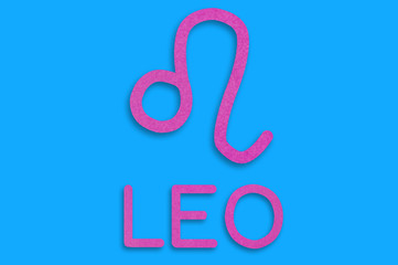Symbol of astrological sign and word leo cut out of purple paper on blue table. Top view. Horoscope concept