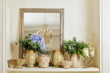Fototapeta na wymiar mirror, beige set with and flowers on shelf