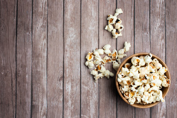Salt popcorn on the wooden table. Popcorn in a wooden bowl.