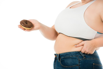 cropped view of overweight woman holding sweet doughnut and touching belly isolated on white, dieting concept