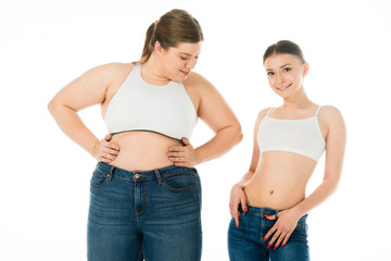 slim and overweight women in denim posing together isolated on white, body positivity concept