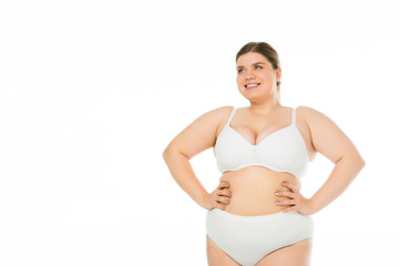 Fototapeta premium smiling overweight girl in underwear with hands on hips isolated on white, body positivity concept