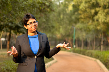 Young Indian woman working business professional expressing and exclaiming wonder and smiling in a formal corporate business suit in an outdoor location