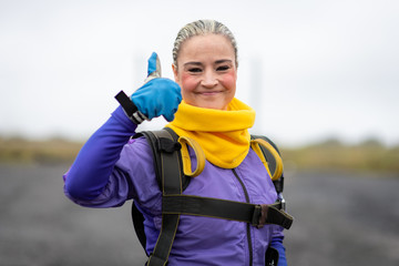 Pretty woman happy, dressed in jumpsuit and parachute harness on airport runway ready for skydive...