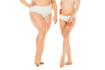 partial view of slim and overweight women in underwear posing together isolated on white, body...