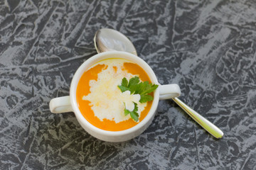 pumpkin soup puree with cream and parsley on grey background