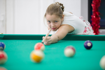 Girl playing billiards.Daughter playing pool