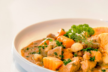 Background of crock pot pork slow cooking with sauce, onions, carrots, pumpkin, served with mix mashed potatoes, isolated on white. homemade dish.   