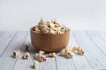 Salt popcorn on the wooden table. Popcorn in a wooden bowl.