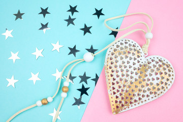 Unusual decorative metal heart on a blue-pink background with silver stars.