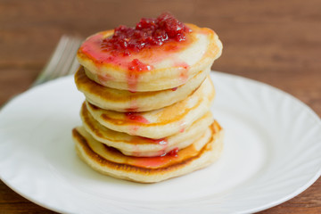 stack of pancakes with raspberry jam on a white plate