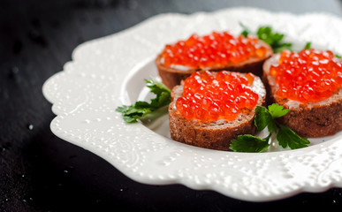 red caviar on black bread with butter. Healthy food. Fish appetizer. dark background