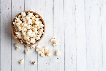 Salt popcorn on the wooden table. Popcorn in a wooden bowl.