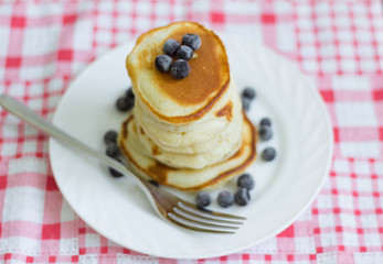 stack of pancakes with black currant berries on a white plate