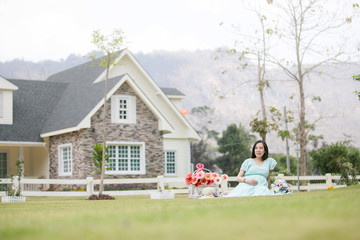 Fototapeta na wymiar Pregnant Woman Sitting at front yard