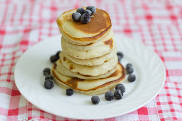 stack of pancakes with black currant berries on a white plate
