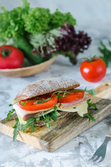 Delicious ciabatta sandwich with ham, tomatoes and arugula.