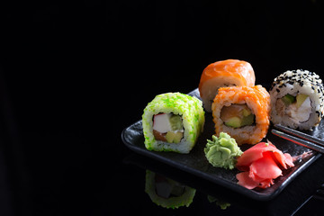 Large sushi sets with lots of sushi, roll . Stylish sushi sets on a black ceramic plane and table with Chinese sticks. Copy space
