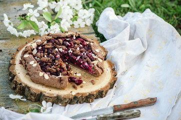 Chocolate cherry galette or pie on a wooden board. Spring or summer picnic in nature.