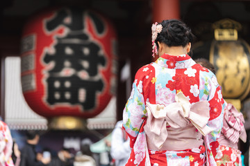 Young girl wearing Japanese kimono standing in front of Sensoji Temple in Tokyo, Japan. Kimono is a...