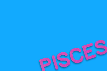 Word pisces cut out of purple paper on blue table. Top view. Horoscope concept