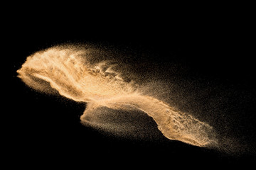 Golden sand explosion isolated on black background. Abstract sand cloud. Golden colored sand splash against dark background. Yellow sand fly wave in the air.