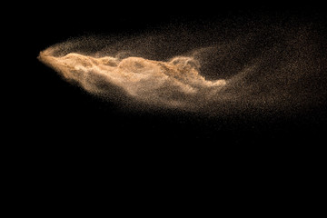 Golden sand explosion isolated on black background. Abstract sand cloud. Golden colored sand splash against dark background. Yellow sand fly wave in the air.