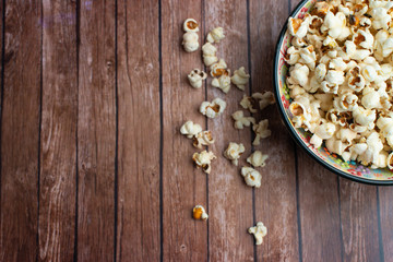 Salt popcorn on the wooden table. Popcorn in a wooden bowl.