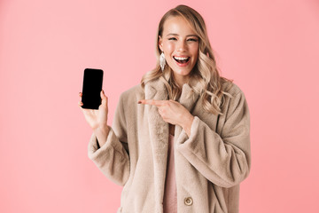 Beautiful happy young pretty woman posing isolated over pink wall background showing display of mobile phone.