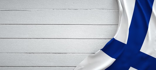 Finland flag, on top of white wood. Wrinkled fabric.
